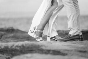 Couple's feet on rocky beach, romantic moment.